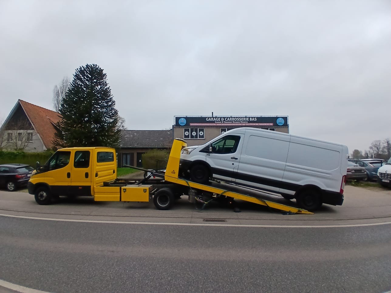 Witte bestelbus wordt op het plateau van een sleepwagen van Faster getrokken