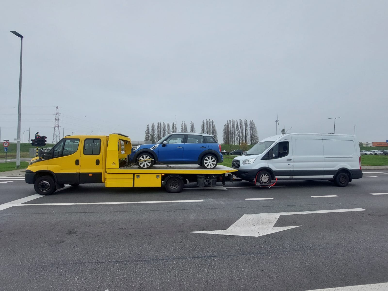 Sleepwagen van Faster met een auto op het plateau en een bestelbus aan de takel