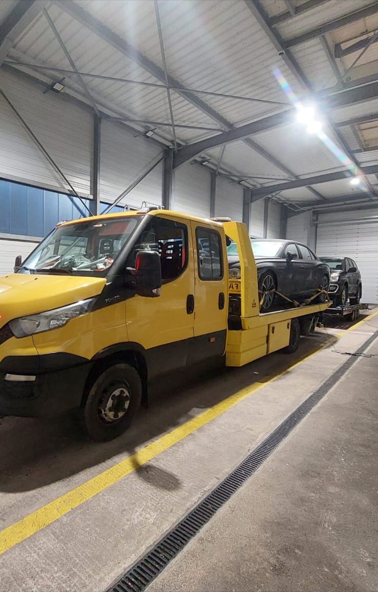 Sleepwagen van Faster met een auto op het plateau in een loods
